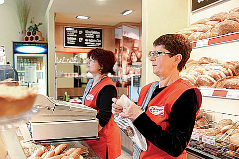 Verkäuferinnen einer Bäckerei verkaufen Backwaren
