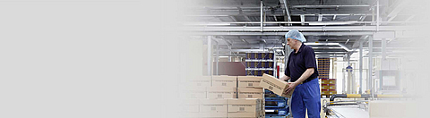 Mann in Verpackungshalle setzt Kartons um